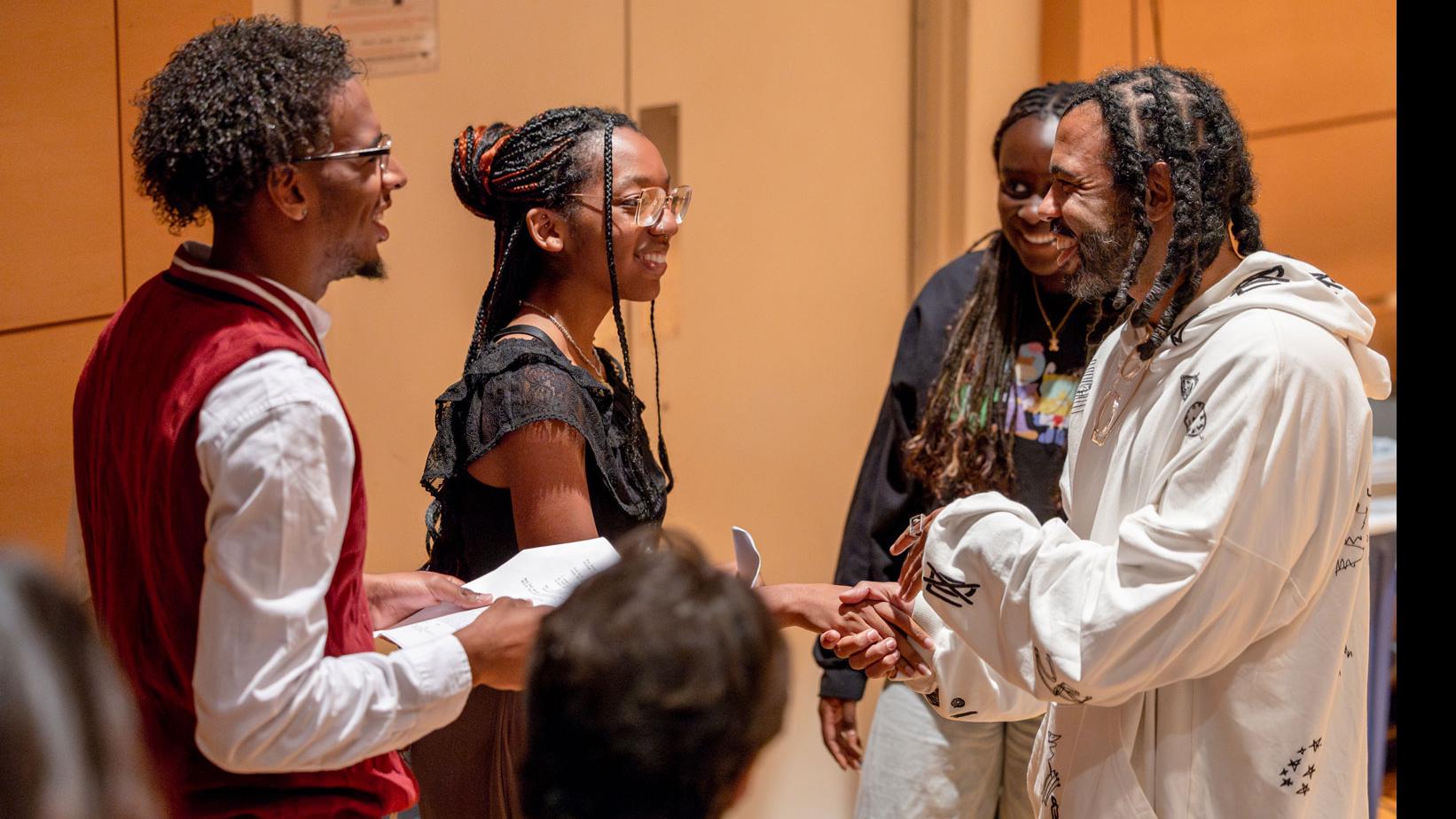 Daveed Diggs shakes hands with a student in a semi-circle of students in the Class of ’56 Dance Studio Theatre.