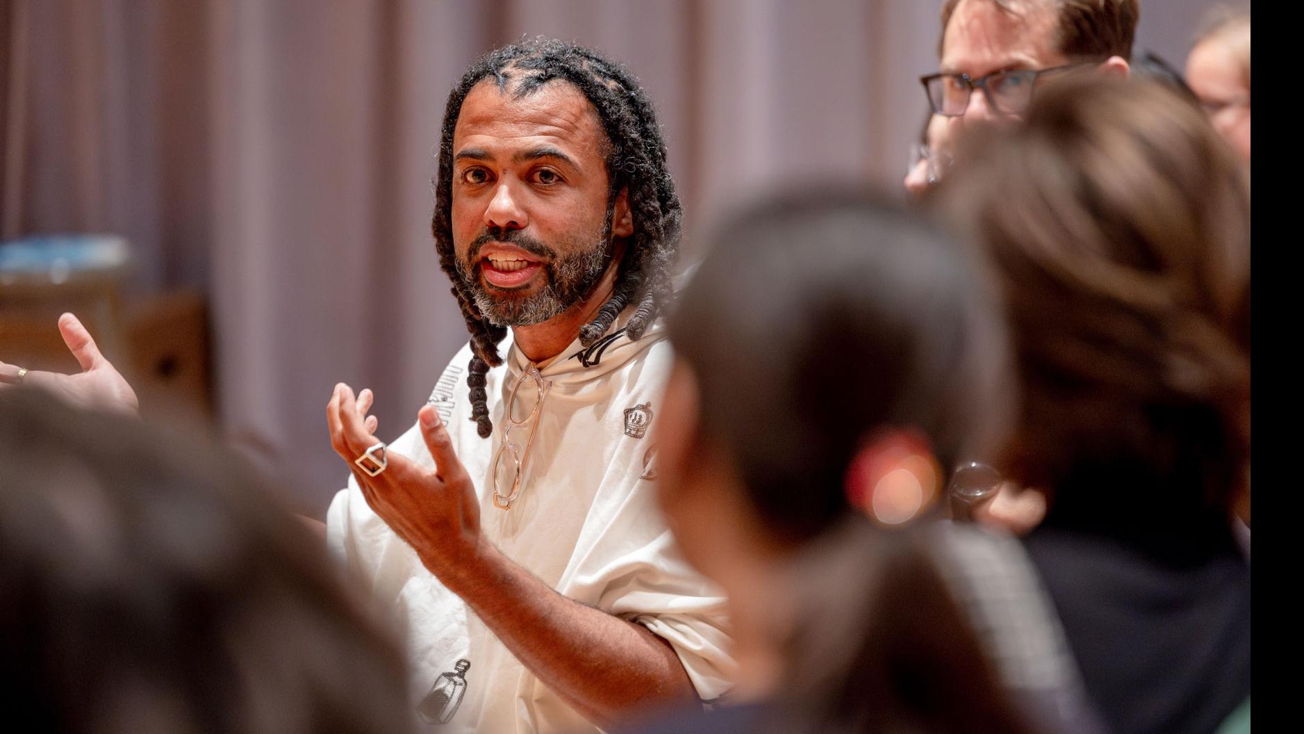 Close up of Daveed Diggs speaking with students, while Diggs, PMA Senior Lecturer Theo Black, and students are seated in the audience in the Class of ’56 Dance Studio Theatre.