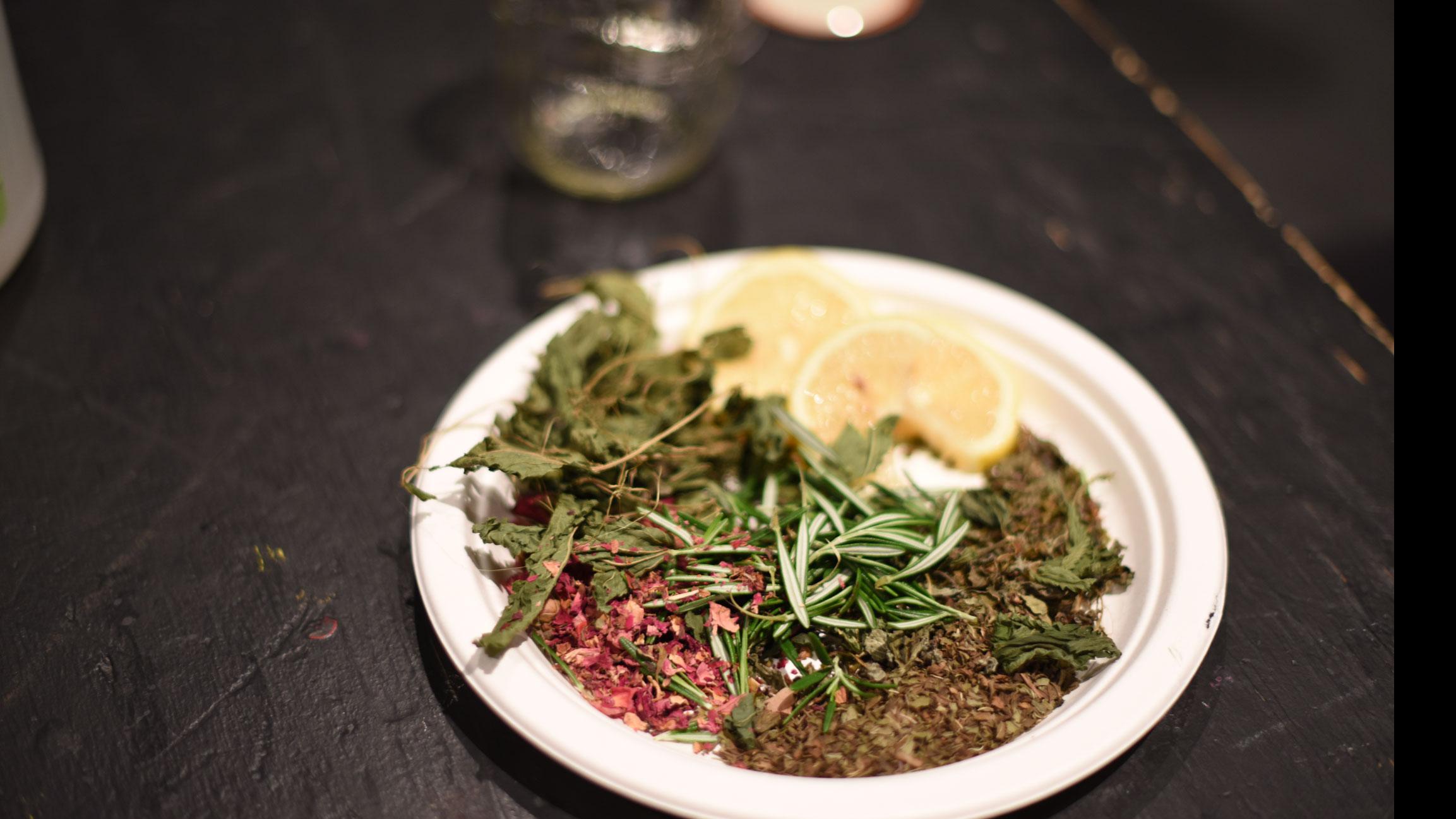 A paper plate with lemon slices and whole and ground spices.