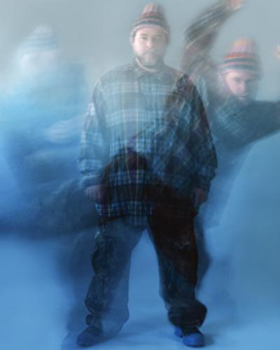 Christopher Matthews in three blurred movement poses facing the camera against a blue background