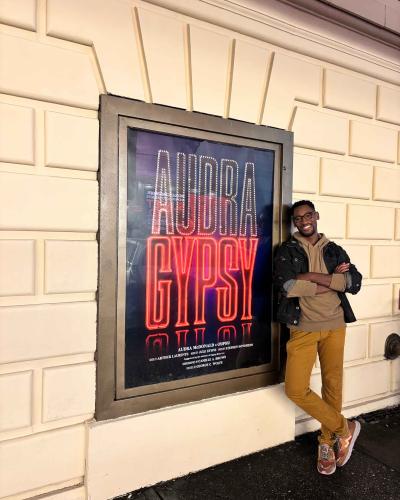 Allen Porterie leaning against a sign that says AUDRA and GYPSY.